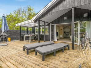 A wooden deck with two lounge chairs, a barbecue grill, and a glass-enclosed patio area. - "Irma" - 300m from the sea by Interhome (Hadsund)