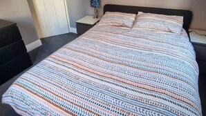 Ein Schlafzimmer mit einem großen Bett, einem Nachttisch mit Lampe und einem Kleiderschrank.