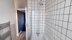 Ein Badezimmer mit einer Badewanne, gefliesten Wänden und einer Duschbrause.