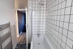 Ein Badezimmer mit einer Badewanne, gefliesten Wänden und einer Duschbrause.