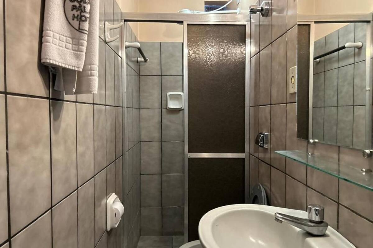 A modern bathroom with a large sink, a glass shower enclosure, and a towel hanging on the wall.