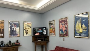 A living room with a red sofa, a television, and a wooden table with decorative items. - Goiânia Palace Hotel (Goiânia)