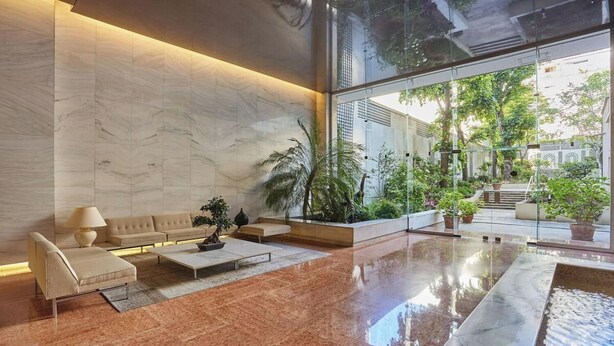 Eine moderne Lobby mit Marmorboden, einer Couch, einem Couchtisch und einem großen Fenster mit Blick ins Freie.