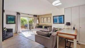 Ein modernes Wohnzimmer mit einer Couch, einem Couchtisch und einem Esstisch. Eine Glasschiebetür führt in einen Außenbereich.
