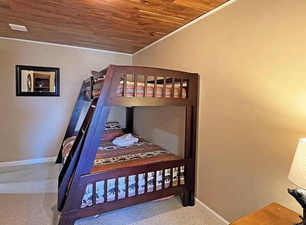 Un lit superposé avec une couvre-lit à motifs et une tête de lit en bois.