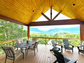 Une terrasse couverte, dotée d’une table et de chaises, qui offre une vue sur un paysage montagneux.