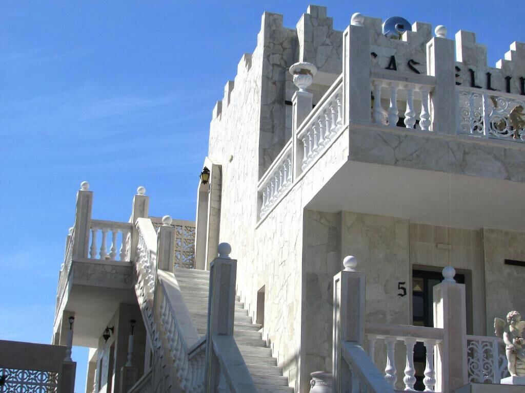 Un edificio de estilo castillo con una gran escalera y un balcón con barandilla.