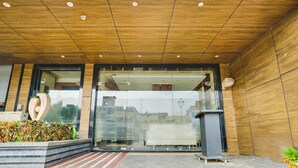 Ein moderner Gebäudeeingang mit Holzboden, Glasüren und einem kleinen Mülleimer.