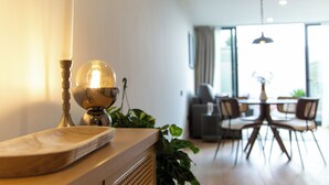 A modern living room with a wooden coffee table, a candle, and a decorative globe. There is a dining area with a table and chairs in the background. - The 153 Hotel (València)