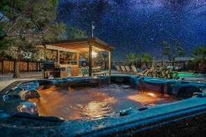 A hot tub area with a wooden pergola and lounge chairs, surrounded by trees and a wooden fence. - Indigo Sky Oasis - Pool & Hot Tub 4 Bedroom Home (Yucca Valley)