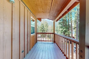 A wooden deck with a railing, a window, and a view of trees. - 40 J7 at Wallowa Lake (Joseph)