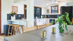 Une cuisine moderne dotée d’un îlot central, de tabourets de bar et d’une table à manger.