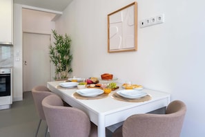 Eine moderne Küche mit weißen Schränken, einem Einbauofen und einem Essbereich mit einem für das Frühstück gedeckten Tisch.