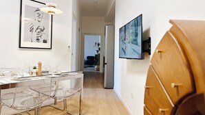 Eine moderne Küche mit Esstisch, Stühlen und einem an der Wand befestigten Fernseher.