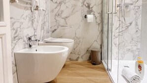 Ein modernes Badezimmer mit einem gebogenen Waschbecken, einer Toilette und einer Duschkabine aus Glas.