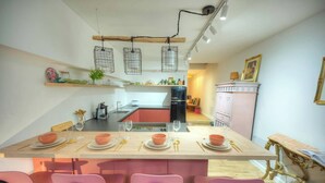 Una cocina moderna con una isla central, sillas rosadas y una mesa de comedor para cuatro.