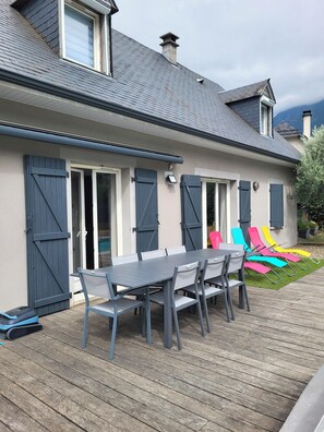 A house with a covered patio, a dining table with chairs, and colorful lounge chairs. - HOUSE IN THE HAUTES-PYRÉNÉES (65260) IN VILLELONGUE WITH A SWIMMING POOL (Villelongue)