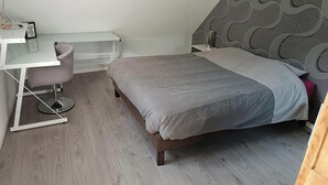 Ett sovrum med en säng, ett skrivbord och en stol.