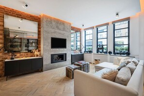 A modern living room with a fireplace, large windows, and a brick accent wall. - Ultra-luxury Pavilion Road Mews Chelsea (London)