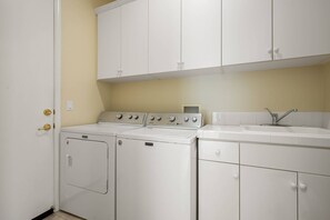 A laundry room with a washing machine, dryer, and a sink. - Stunning Private Pool Home Overlooking the 8th and 9th Double Fairway in PGA (La Quinta)
