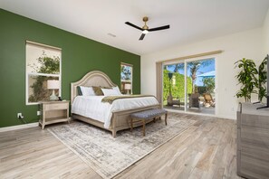 A bedroom with a bed, bedside tables, a bench, a ceiling fan, and a view through a glass door. - Stunning Private Pool Home Overlooking the 8th and 9th Double Fairway in PGA (La Quinta)
