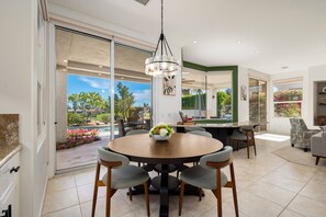 A modern dining area with a round table, chairs, and a chandelier. - Stunning Private Pool Home Overlooking the 8th and 9th Double Fairway in PGA (La Quinta)