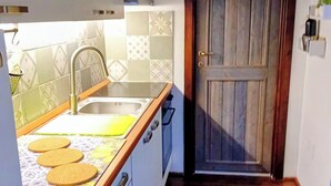 Uma cozinha com bancada de madeira, pia e porta com moldura de madeira.