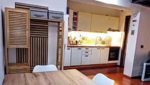 Uma cozinha moderna com armários brancos, uma mesa de jantar de madeira e uma cadeira branca.