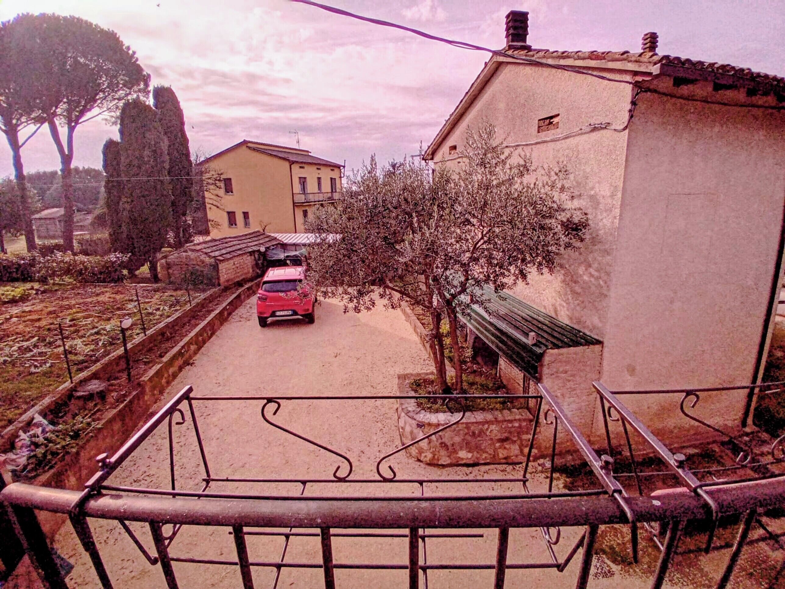 Una strada residenziale con un'auto rossa parcheggiata di fronte a una casa.