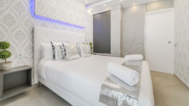 Een moderne slaapkamer met een groot bed, een nachtkastje en een tv aan de muur.