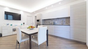 Una cocina moderna con armarios blancos, horno empotrado y un ventanal amplio.