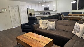 Ein modernes Wohnzimmer mit einem braunen Sofa, einem Holztisch und einem schwarzen Ledersessel.