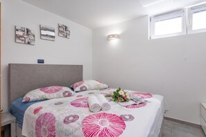 Ein Hotelzimmer mit einem Bett, Kissen, einem Nachttisch, einer Wanduhr und Kunstwerken.