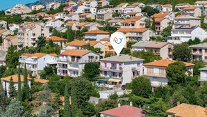Zona residencial con varios edificios de apartamentos, algunos con balcones y paneles solares, rodeada de vegetación.