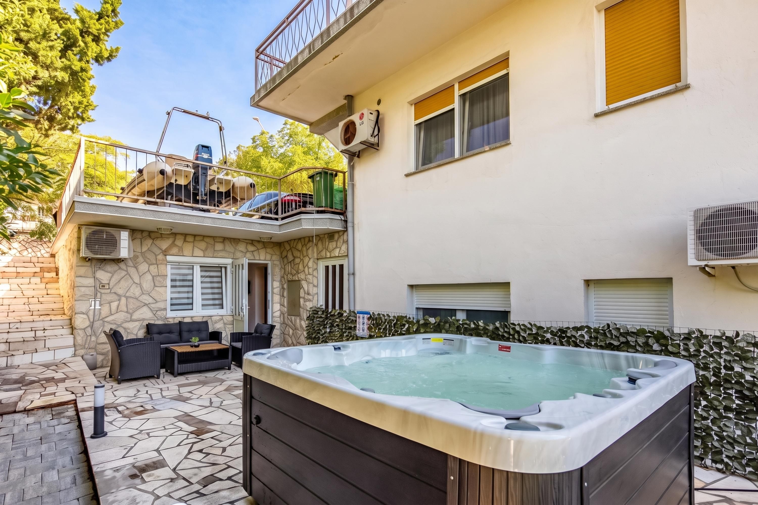 A residential building with a hot tub, outdoor seating, and a stone wall.