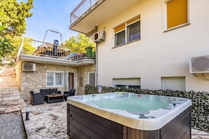 Un immeuble résidentiel doté d’un jacuzzi, d’un espace extérieur aménagé et d’un mur en pierre.