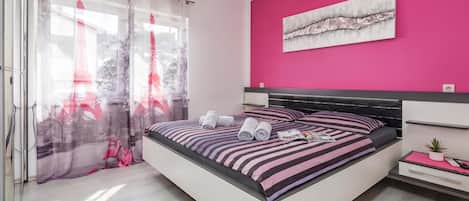 Un dormitorio moderno con cama, mesita de noche, una pequeña planta en maceta y aire acondicionado instalado en la pared.