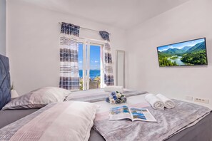 A hotel room with a bed, a window with curtains, a television, and a view of a landscape. - Comfortable Seaview Apartment Pacco (Novi Vinodolski)