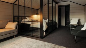 A modern bedroom with a glass partition, a bed, a sofa, and a chair. - Northern Lights Village Ivalo (Inari)