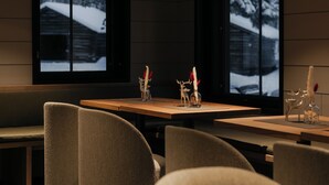 A modern interior with a stone floor, wooden tables, and cushioned chairs. - Northern Lights Village Ivalo (Inari)