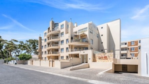 A multi-story residential building with balconies, a central staircase, and a gated entrance. - Coral Grove (Cape Town)