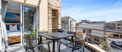 A balcony with a bed, a table, and chairs.