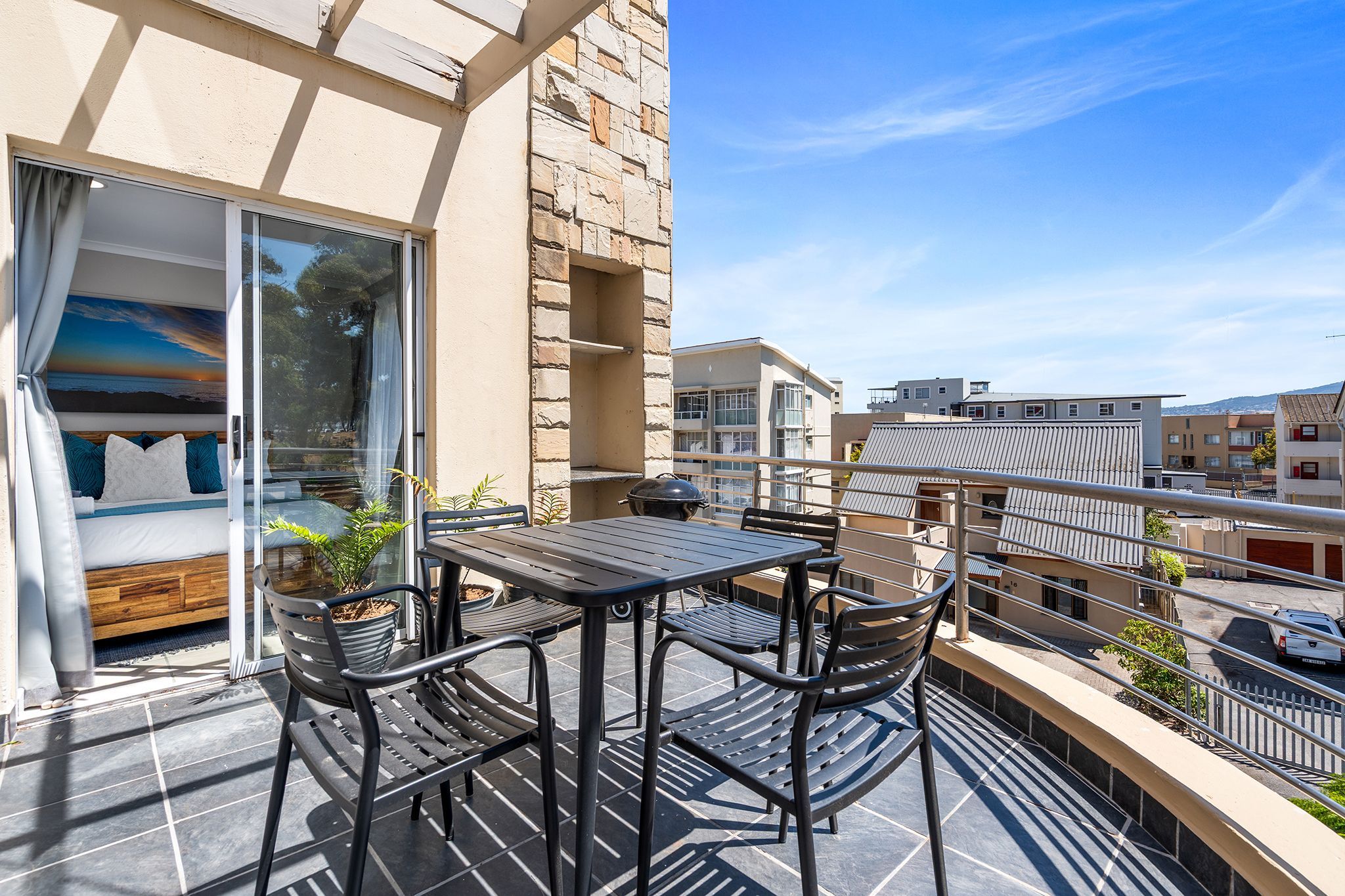 A balcony with a bed, a table, and chairs.