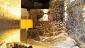 A stone-walled interior with a cushioned bench, a lamp, and a stone fireplace. - Villa in the Ribeira Sacra, A Chalana (Pantón)