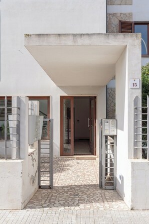 A building entrance with a tiled patio, a covered area, and a number '15' sign. - The Terrace on the Gulf of Alghero 1 (Alghero)