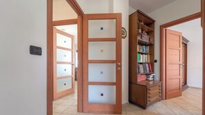 Ein Flur mit einer Holztür, einem Bücherregal und einem Fliesenboden.
