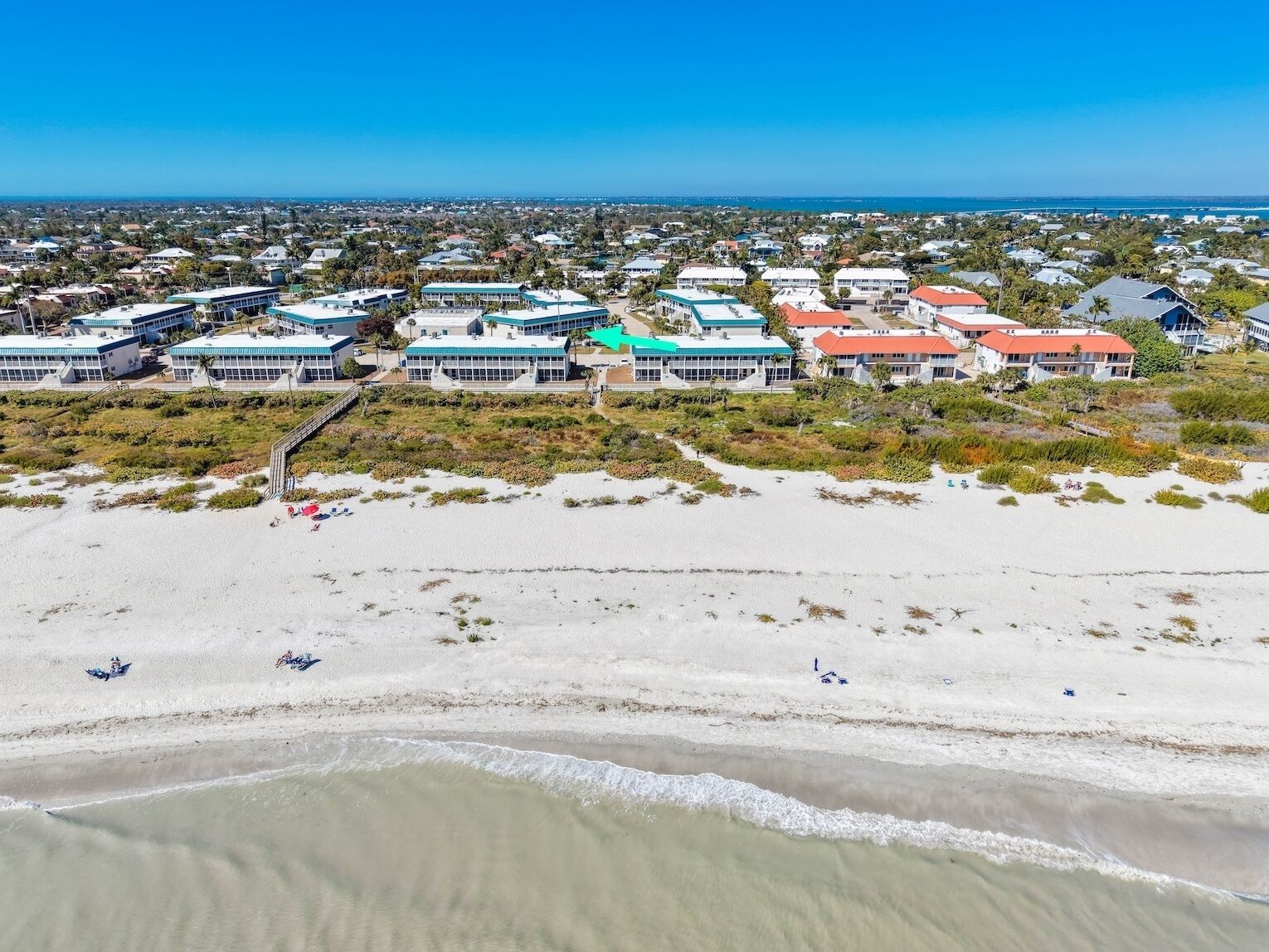 A coastal area with beachfront properties, including a large building with a green roof and several smaller buildings with red roofs.