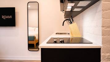 Een moderne keuken met een aanrecht, spoelbak en een spiegel die een bed weerspiegelt.