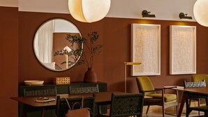 A dining area with a round mirror, a vase with greenery, and two framed abstract artworks on the wall. - Roami at The Fitz (St. Paul)