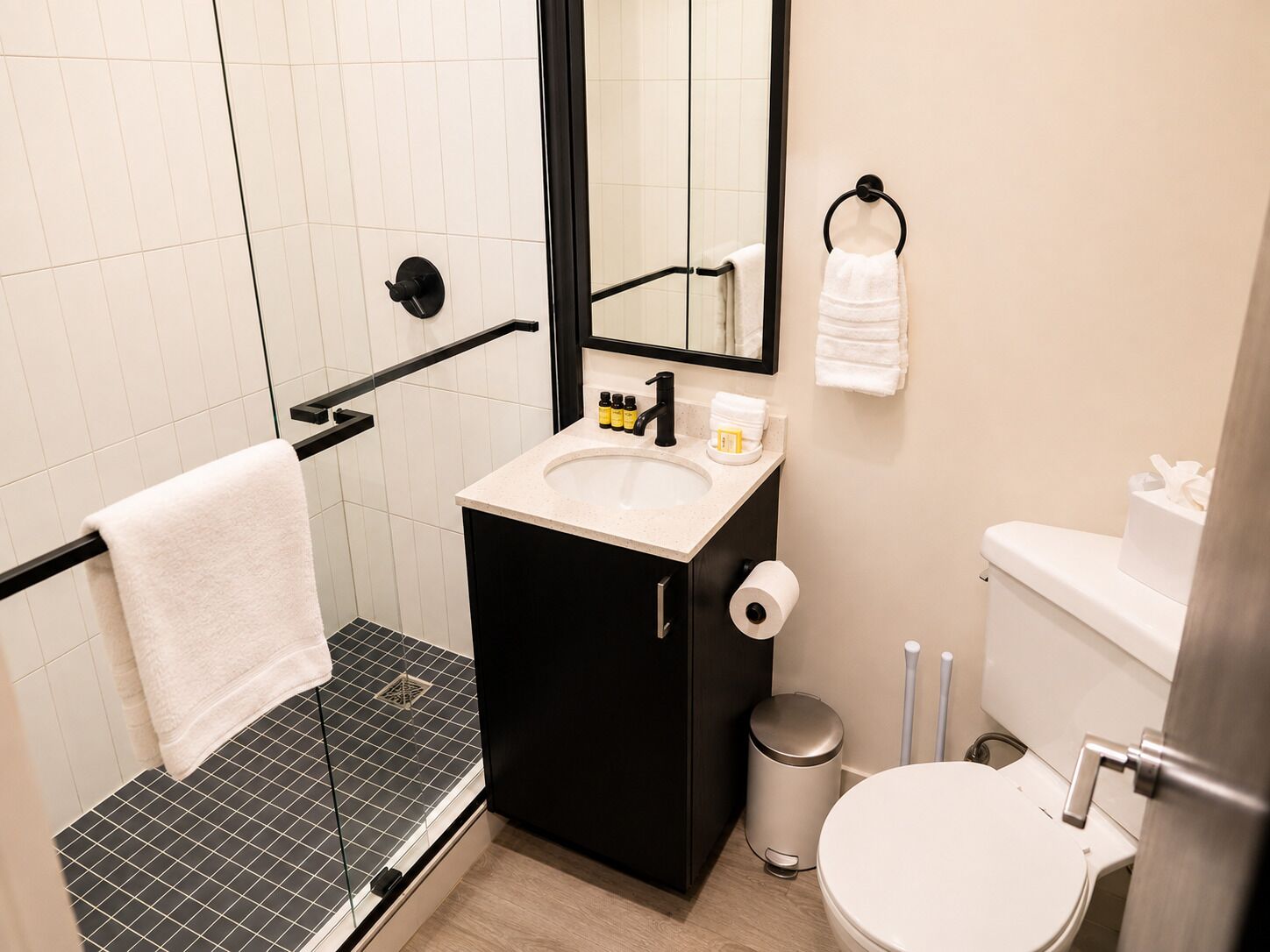 A modern bathroom with a shower, toilet, sink, and a mirror.